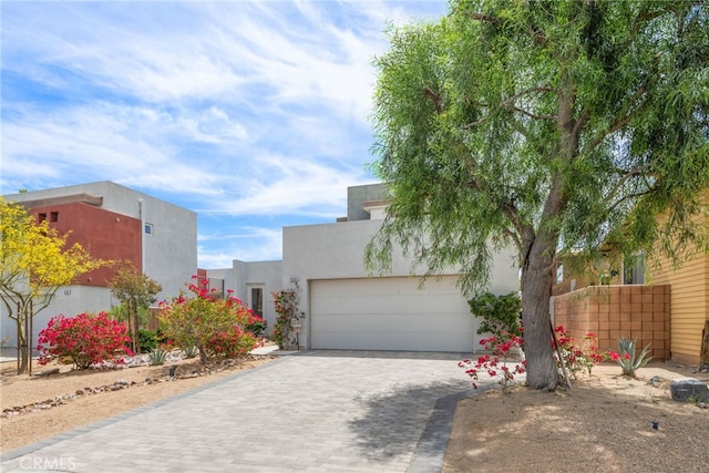 view of front of home featuring an attached garage, decorative driveway, and stucco siding