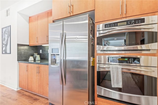 4934 Herzog Way, Palm Springs, CA 92262 - kitchen featuring appliances with stainless steel finishes, light wood-type flooring, tasteful backsplash, and dark countertops