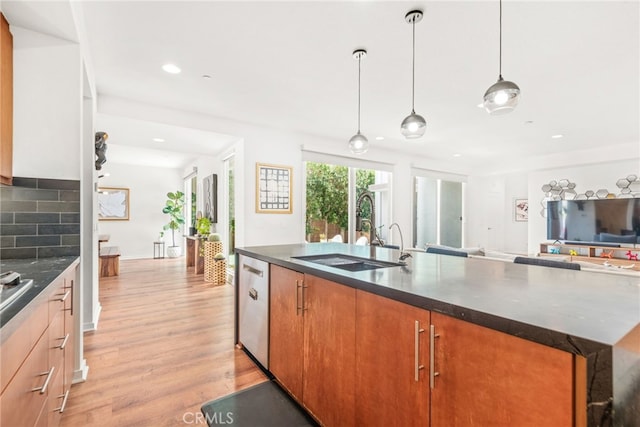 kitchen with a sink, open floor plan, light wood-style floors, dishwasher, and an island with sink