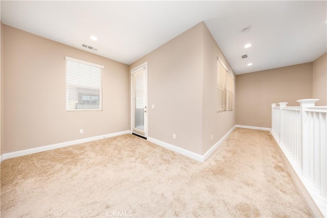 unfurnished room with visible vents, baseboards, and light carpet