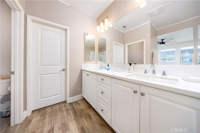 bathroom featuring double vanity, visible vents, a sink, and wood finished floors