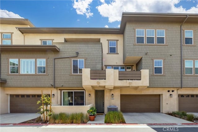 townhome / multi-family property with a garage, stucco siding, and driveway