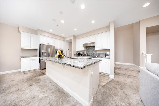 kitchen with light carpet, baseboards, a kitchen bar, stainless steel refrigerator with ice dispenser, and under cabinet range hood