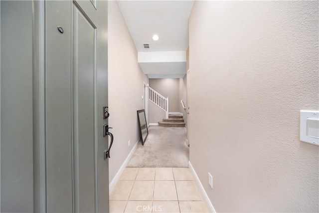 corridor featuring light tile patterned floors, baseboards, stairway, and visible vents