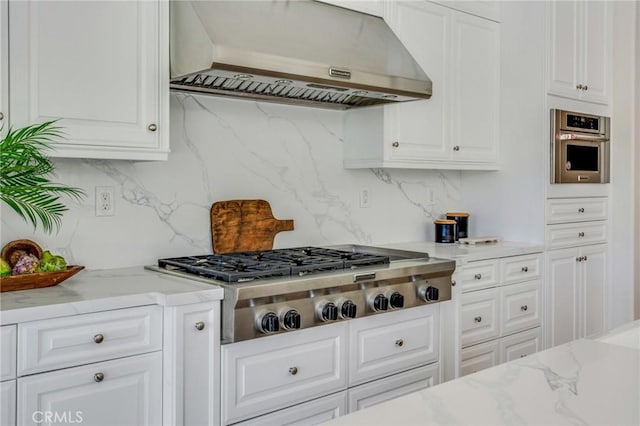 kitchen featuring light stone countertops, extractor fan, stainless steel appliances, white cabinetry, and decorative backsplash