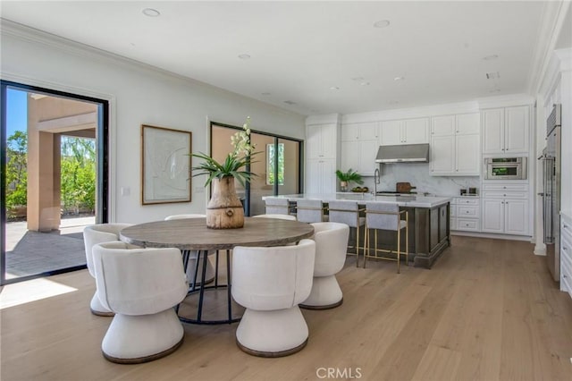 dining area with light wood-style floors and crown molding