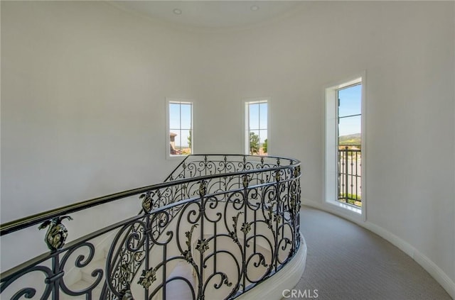 corridor featuring baseboards, carpet flooring, and an upstairs landing
