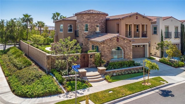 mediterranean / spanish-style house with fence, an attached garage, stucco siding, a tiled roof, and driveway
