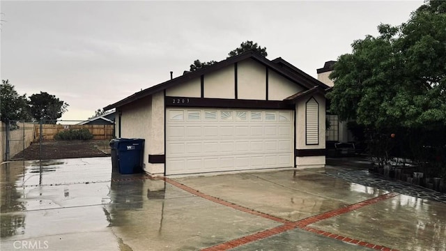 garage featuring fence and concrete driveway