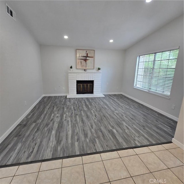 unfurnished living room featuring visible vents, a brick fireplace, wood finished floors, baseboards, and recessed lighting