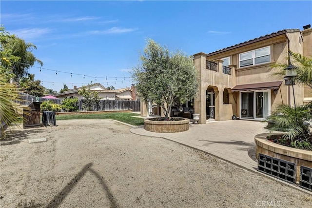rear view of property featuring stucco siding, a patio area, and fence