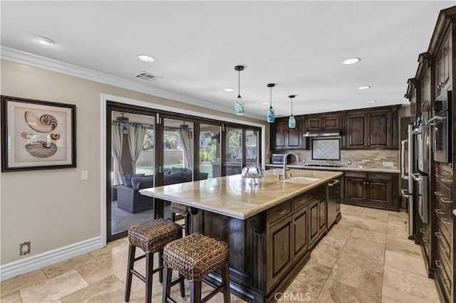 kitchen with a kitchen breakfast bar, visible vents, appliances with stainless steel finishes, a sink, and baseboards