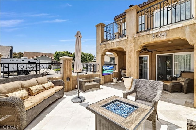 view of patio with a balcony and an outdoor living space with a fire pit
