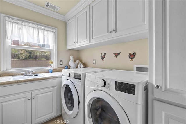 washroom featuring cabinet space, a sink, separate washer and dryer, visible vents, and ornamental molding