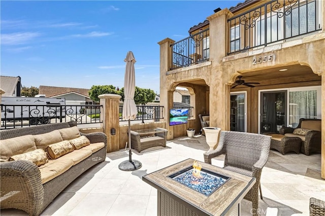 view of patio featuring an outdoor living space with a fire pit and a balcony