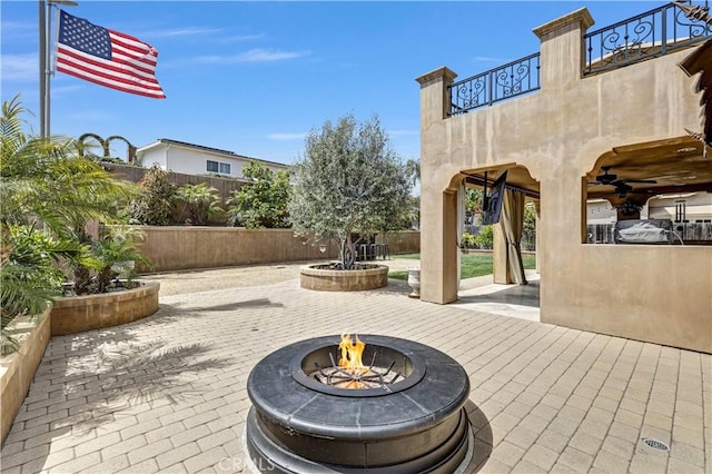 view of patio / terrace featuring fence, ceiling fan, an outdoor fire pit, and a balcony
