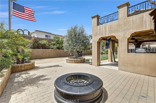 view of patio / terrace featuring a ceiling fan, an outdoor fire pit, fence, and a balcony