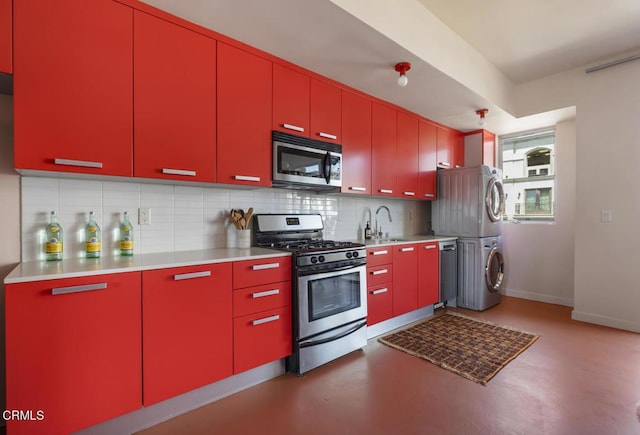 kitchen with red cabinets, stacked washing maching and dryer, and stainless steel appliances