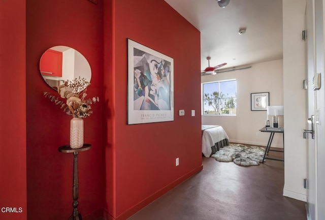corridor featuring baseboards and concrete flooring