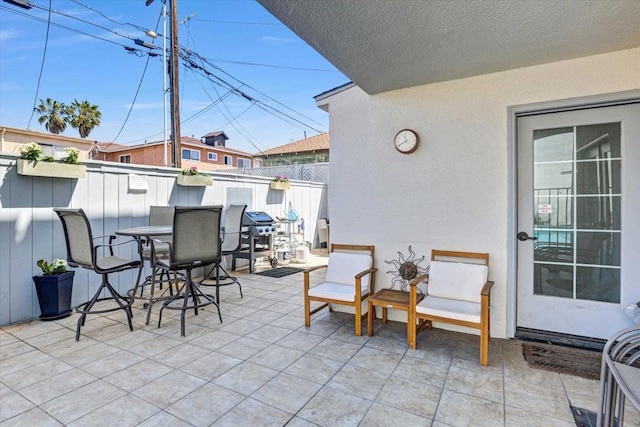 view of patio with outdoor dining area, fence, and area for grilling
