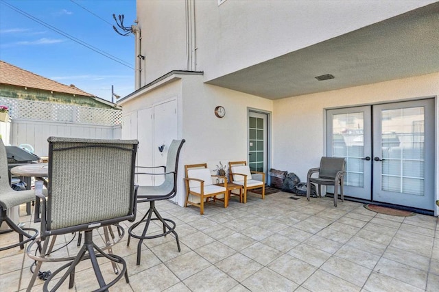 view of patio with french doors, fence, and outdoor dining area