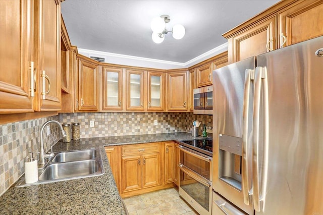 kitchen featuring brown cabinets, backsplash, appliances with stainless steel finishes, and a sink