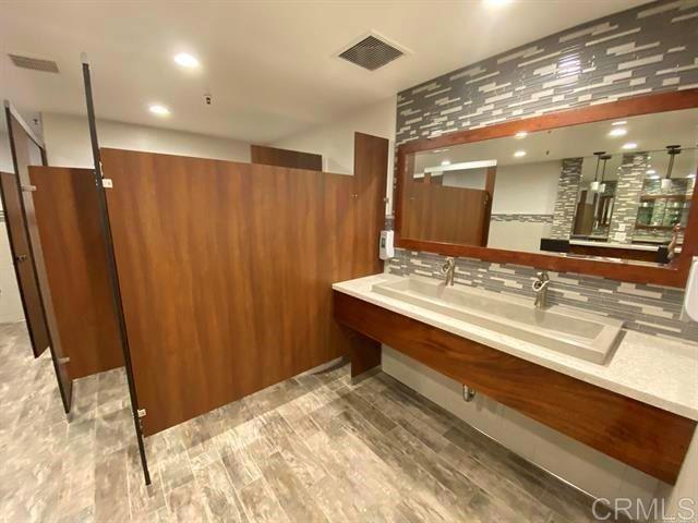 bathroom with visible vents, double vanity, and wood finished floors