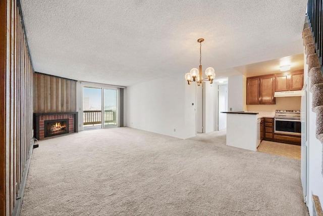 unfurnished living room with light carpet, a fireplace, a textured ceiling, and a chandelier