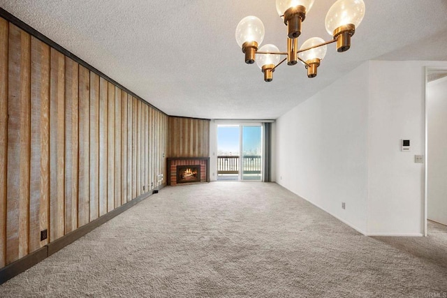 unfurnished living room featuring carpet, a brick fireplace, a textured ceiling, and a notable chandelier
