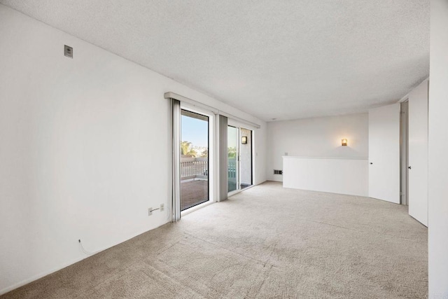 unfurnished room with carpet and a textured ceiling