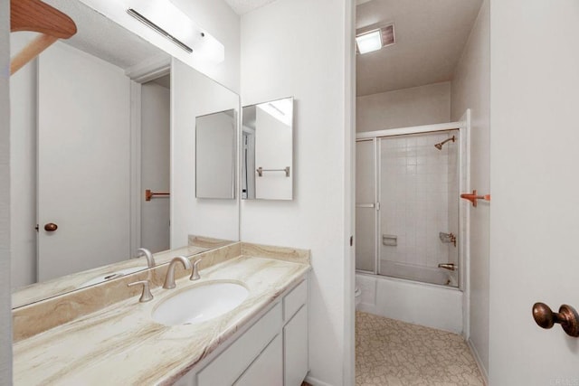 bathroom with vanity, baseboards, shower / bath combination with glass door, and visible vents