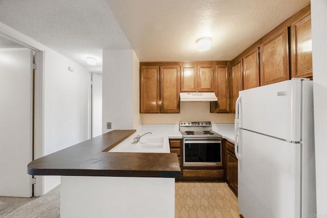 kitchen with a sink, electric stove, freestanding refrigerator, a peninsula, and under cabinet range hood