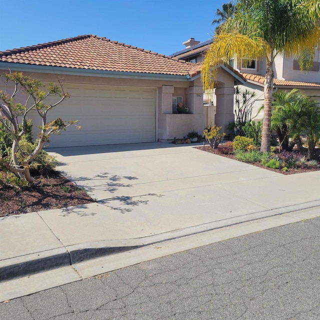 view of front of property featuring an attached garage, stucco siding, driveway, and a tile roof