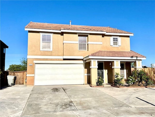 traditional-style house featuring an attached garage, fence, driveway, and stucco siding
