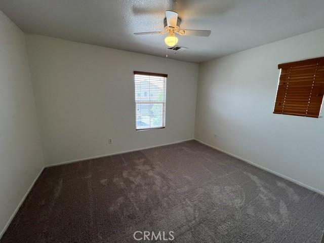 unfurnished room featuring visible vents, carpet flooring, baseboards, and a ceiling fan