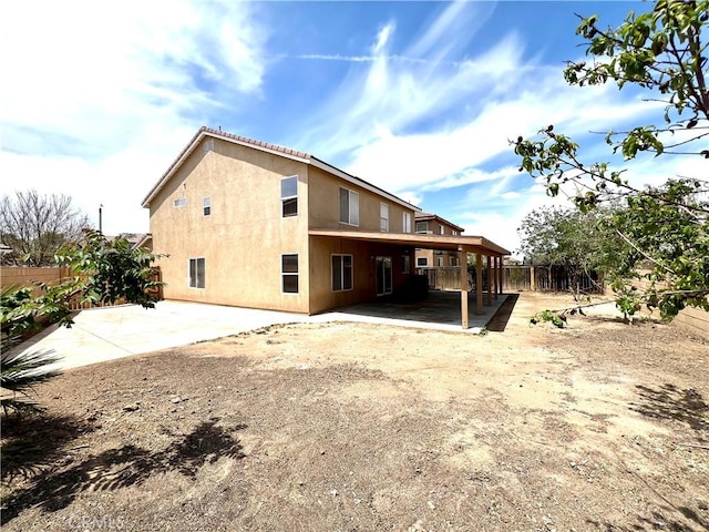 back of house with fence, stucco siding, and a patio area