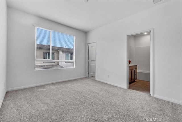unfurnished bedroom featuring baseboards, carpet, and ensuite bath