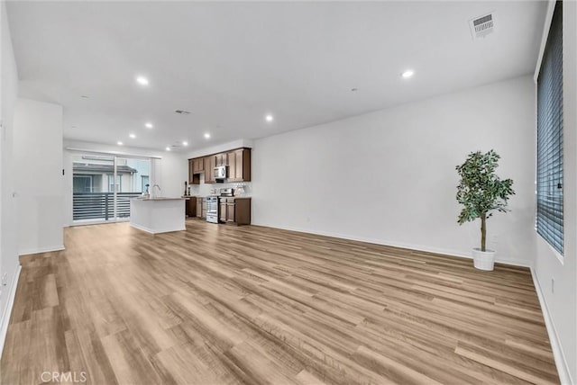 unfurnished living room featuring visible vents, recessed lighting, light wood-style flooring, and baseboards