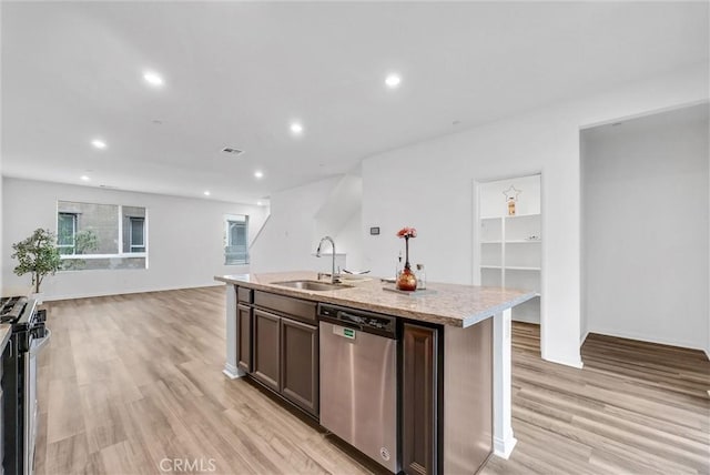 kitchen with a sink, light wood finished floors, an island with sink, stainless steel appliances, and open floor plan