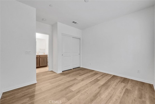 unfurnished bedroom with visible vents, light wood-style flooring, baseboards, and a closet