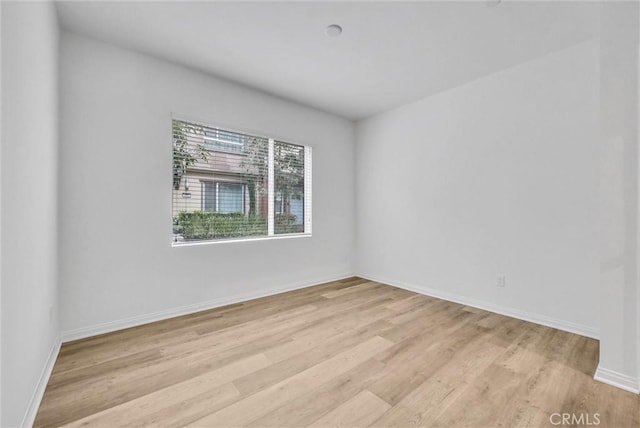 empty room featuring light wood-type flooring and baseboards