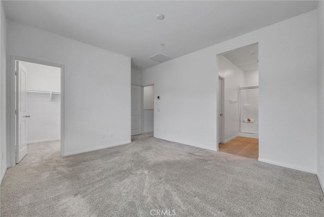 unfurnished bedroom with carpet floors, baseboards, a spacious closet, and a closet