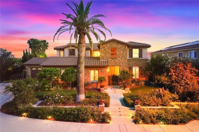 mediterranean / spanish-style house featuring a tile roof and stone siding