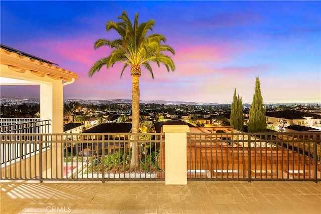 patio terrace at dusk featuring a balcony