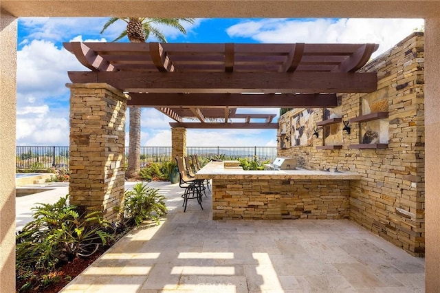 view of patio / terrace featuring exterior bar, fence, a pergola, and an outdoor kitchen