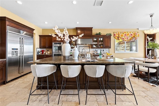kitchen featuring dark countertops, decorative backsplash, stainless steel appliances, and visible vents