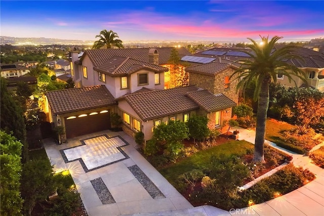 mediterranean / spanish home with a tiled roof, an attached garage, driveway, and stucco siding