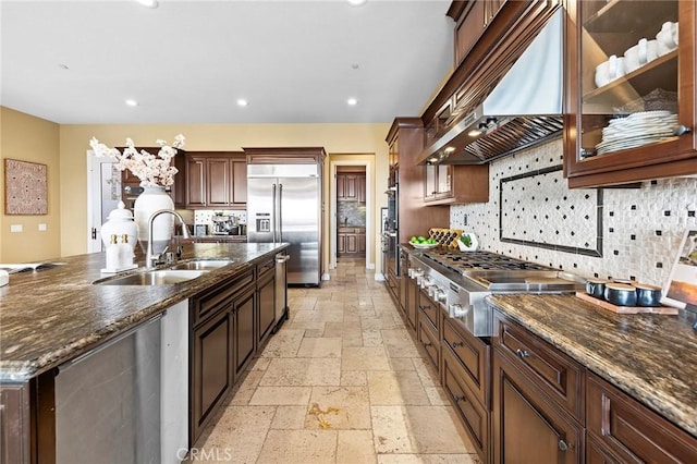 kitchen with a sink, ventilation hood, stainless steel appliances, tasteful backsplash, and stone tile flooring