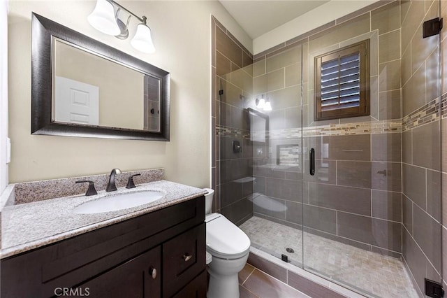 bathroom featuring vanity, tile patterned floors, a stall shower, and toilet