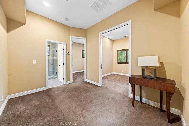 interior space with carpet floors, baseboards, connected bathroom, and visible vents